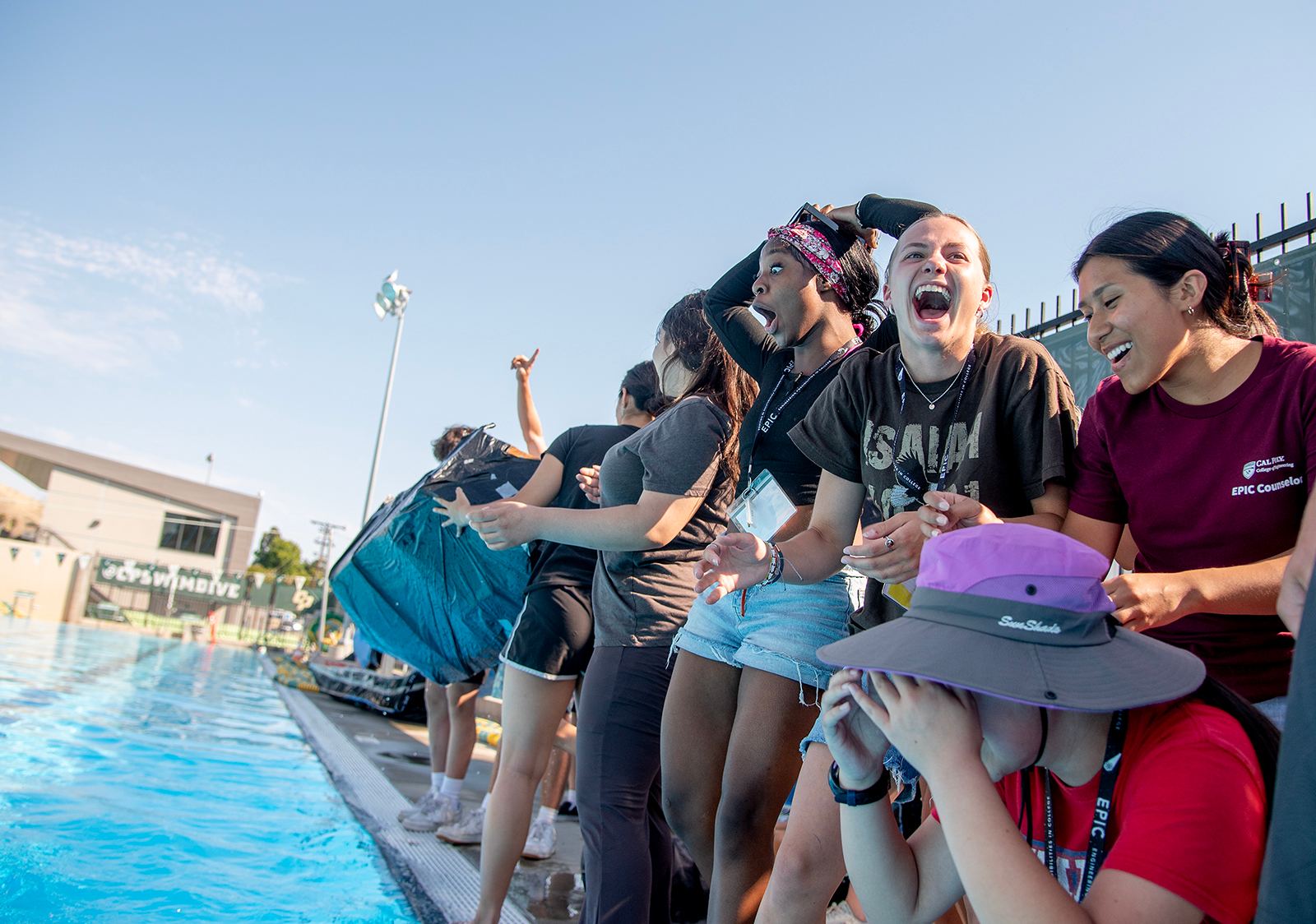 Participants in the EPIC- Engineering Possibilities in College cardboard boat race react as their teammates near the finish line.